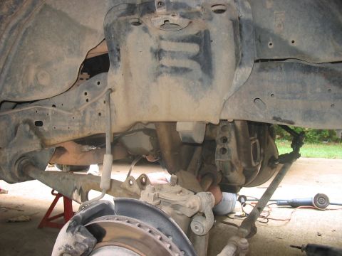 1988 Ford Bronco - Close-up view of the undercarriage of a vehicle, focusing on the suspension and frame components during a lift installation.