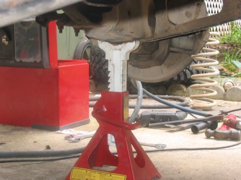1988 Ford Bronco - A vehicle's suspension system is supported by jack stands during maintenance, revealing the springs and undercarriage components.