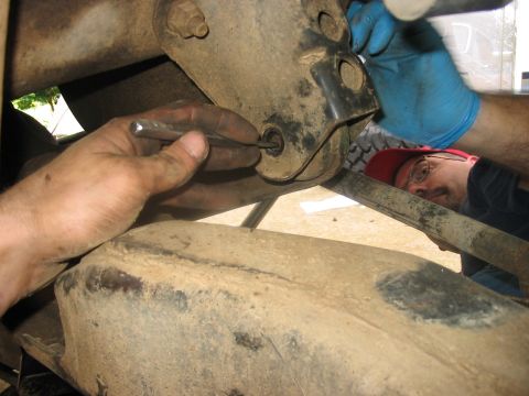 1988 Ford Bronco - Mechanic performs suspension work on a vehicle, with a Supermotors.net watermark visible.