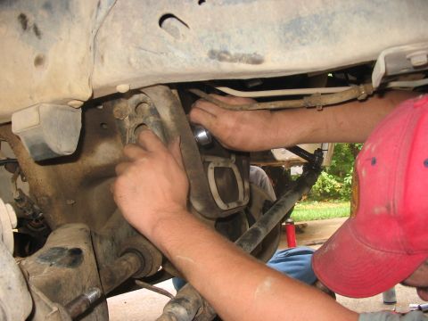 1988 Ford Bronco - Mechanics work on the front suspension of a 1988 Ford Bronco during a lift installation.