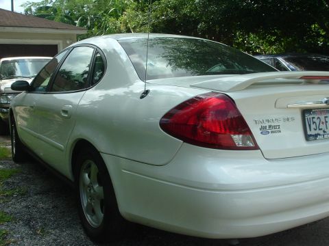 2003 Ford Taurus - A white sedan is parked next to another vehicle, with a clear view of its rear badging and license plate.