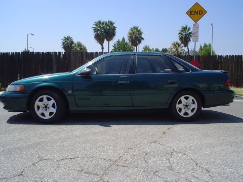 1993 Ford Taurus - Side profile of a 1993 Ford Taurus sedan under a clear sky.