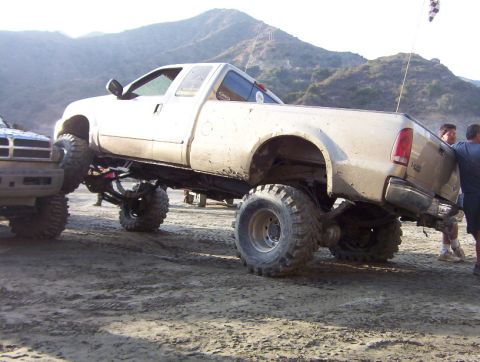 2000 Ford F-450 - A heavily modified pickup truck is shown off-road, with its front end nudging another vehicle.