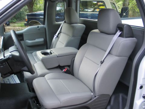 2004 Ford F-150 - The interior of a 2004 Ford F-150 pickup truck, gray cloth seats and a center console. Another vehicle is visible in the background.