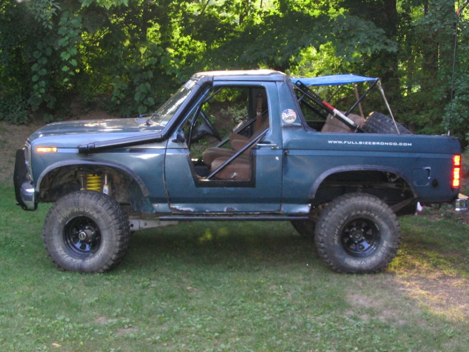 Blue lifted Ford Bronco, side view, doors off, roll cage and blue canopy