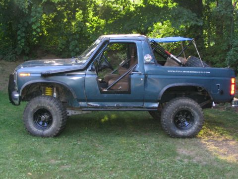1986 Ford Bronco - This modified SUV features a snorkel and roll cage, with a website address visible on the tailgate.