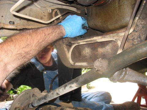 1988 Ford Bronco - A mechanic performs maintenance on a vehicle's undercarriage, focusing on suspension and engine components.