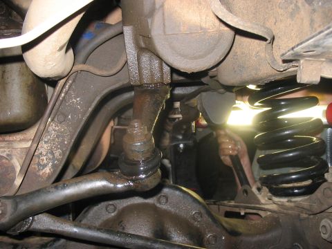 1988 Ford Bronco - Undercarriage view shows steering components and a recently installed black coil spring, likely during a lift kit installation.
