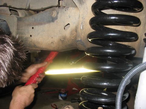 1988 Ford Bronco - Close-up of vehicle suspension work, focusing on a coil spring and frame components.