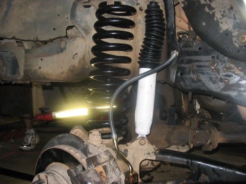 1988 Ford Bronco - Close-up view of the front suspension system, highlighting a new coil spring and shock absorber.