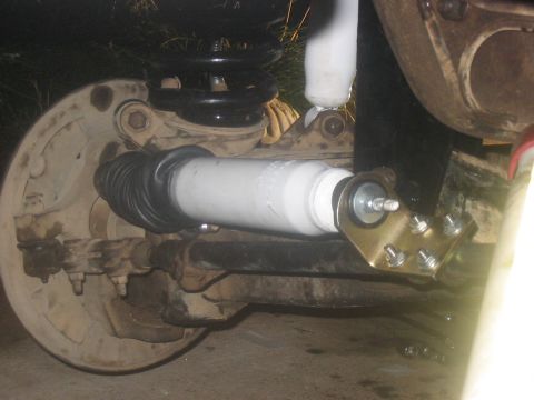 1988 Ford Bronco - Close-up of a vehicle's front suspension system, showing a white shock absorber and black coil spring.