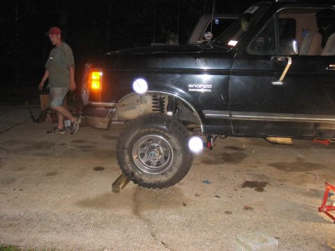 1988 Ford Bronco - A black Ford Bronco is shown with its front wheel elevated, suggesting suspension work or modification.