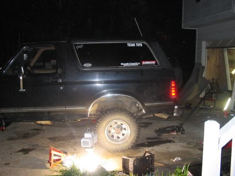 1988 Ford Bronco - A black Ford Bronco is shown from the side, lifted by a jack with tools scattered around.