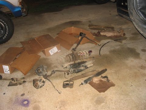 1988 Ford Bronco - Various suspension components, including shocks and springs, are laid out on the ground next to cardboard boxes.