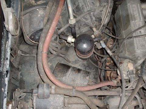 1993 Ford Bronco - Close-up view of engine bay components, including hoses and the AC accumulator.