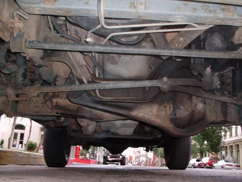 1993 Ford Bronco - The underside of a vehicle is shown, with a dark SUV visible in the background on a city street.