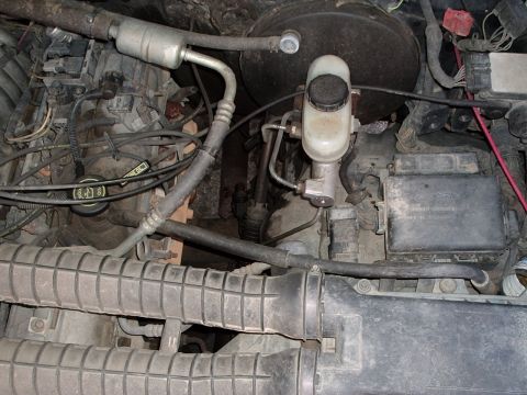 1993 Ford Bronco - Close-up view of an engine bay, showing the brake fluid reservoir, various hoses, and air intake system components.