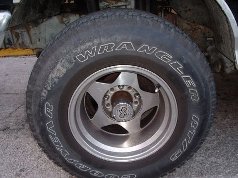 1993 Ford Bronco - A close-up view of a tire and wheel assembly reveals wear and tear on the vehicle's undercarriage.