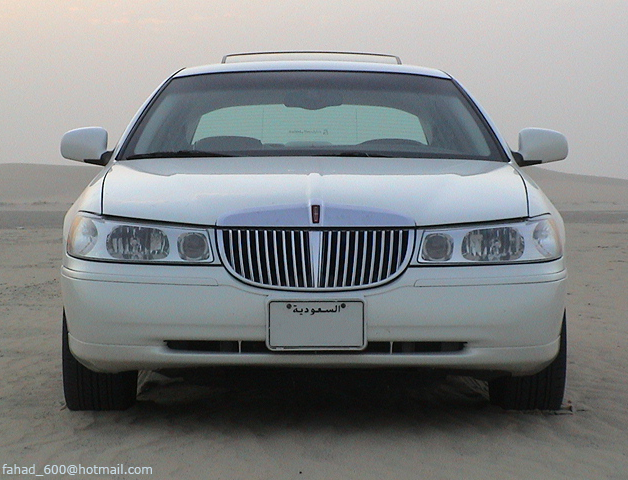White sedan with a chrome grille and a license plate with Arabic text, viewed from the front