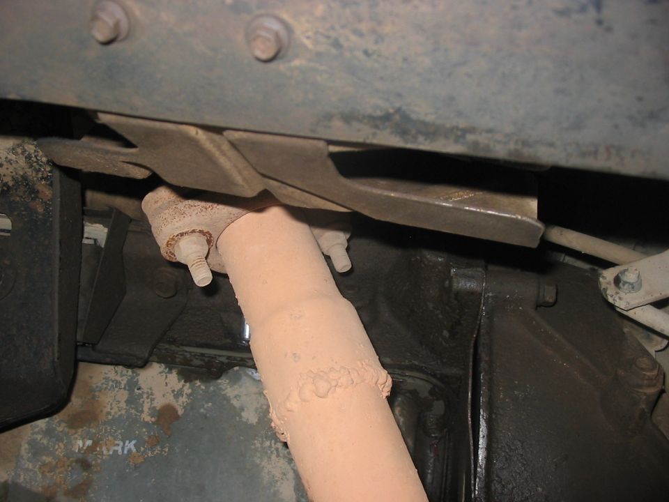Tan-primered welded tube link bolted under a rusty frame rail