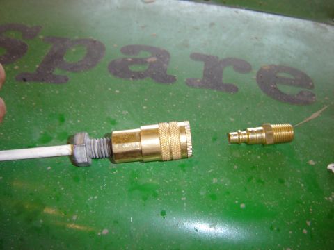 1992 Ford Bronco - Close-up of two brass air compressor quick connect fittings on a green surface.