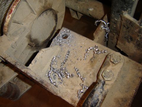 1992 Ford Bronco - Metal shavings litter a bracket, suggesting recent drilling or machining work on a vehicle component.
