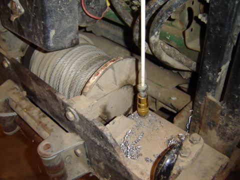 1992 Ford Bronco - Close-up of a winch mechanism a quick disconnect fitting and scattered metal shavings.