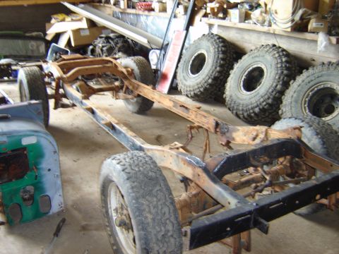 1992 Ford Bronco - Workshop scene shows a heavily rusted vehicle frame with several large tires stacked nearby.