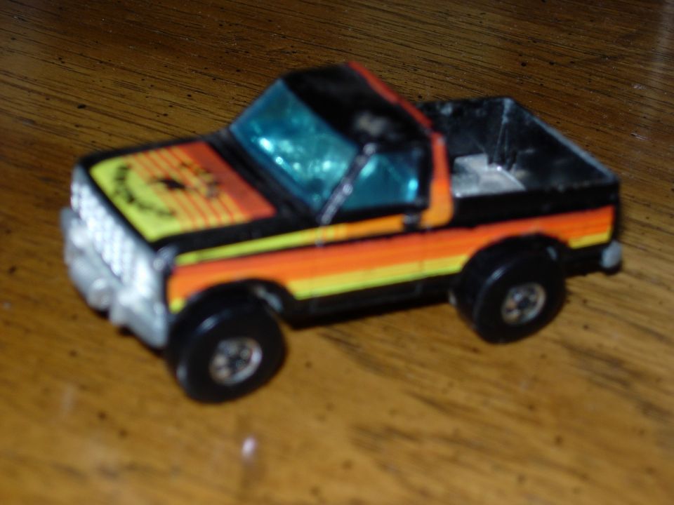 Toy pickup truck with orange and yellow stripes on the side and a sun graphic on the hood