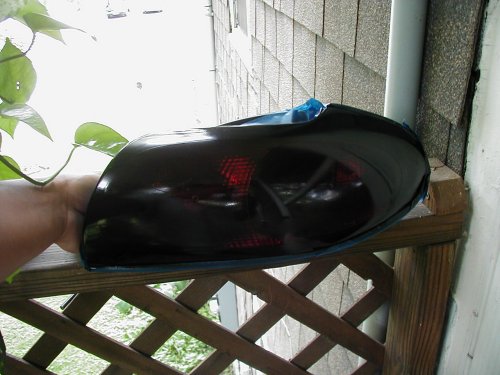 Tinted tail light held by hand, with Supermotors.net logo visible