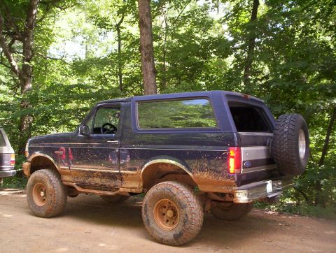 1994 Ford Bronco - This muddy 1994 Ford Bronco is seen off-road, a spare tire mounted on the rear tailgate.