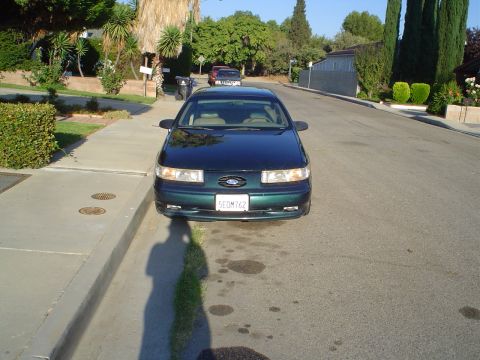 1993 Ford Taurus - A dark green 1996 Ford Taurus is parked on a residential street.