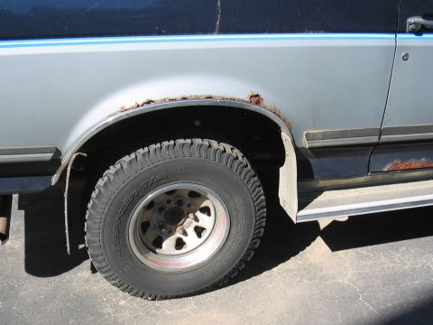 1979 Ford Bronco - This image shows the rear wheel well of a silver SUV, highlighting rust damage on the fender flare and an off-road tire.