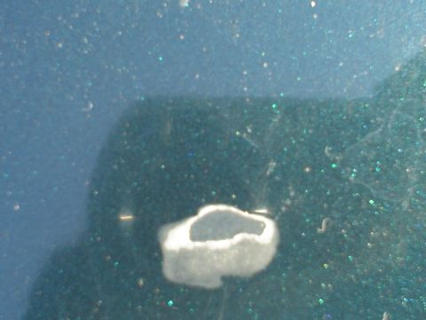 1993 Ford Taurus - A close-up view of damage to the car's paint reveals a chip with exposed primer.