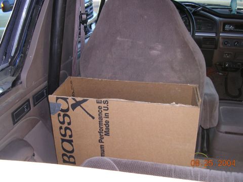 1994 Ford Bronco - Cardboard box sits on the rear seat of a 1994 Ford Bronco. The interior shows the seats and dashboard.