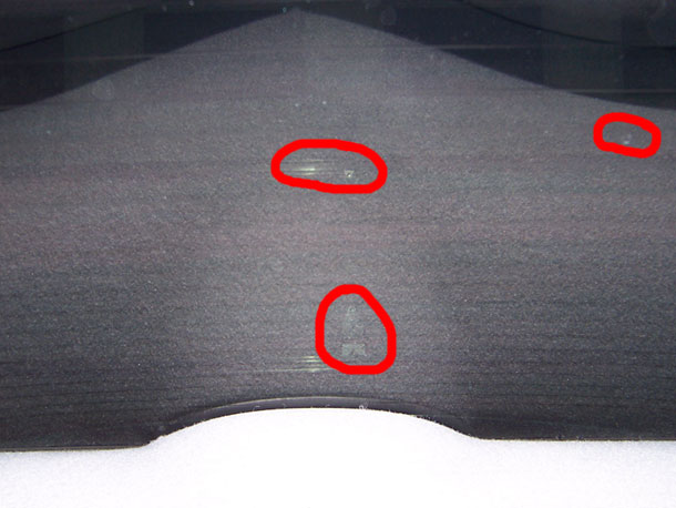 Dark gray textured dashboard with three red circles highlighting scuffs or damage