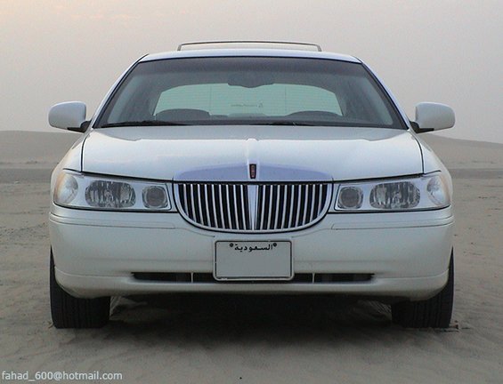 Front view of white Lincoln Town Car on sand, chrome waterfall grille and Saudi plate