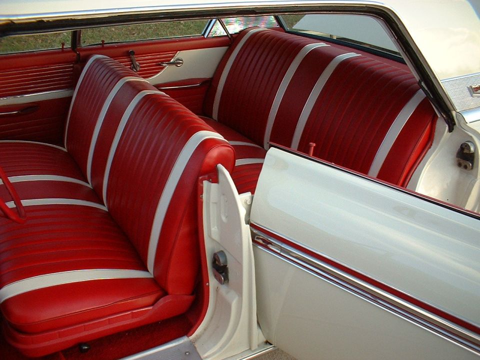 Red and white pleated vinyl bench seat interior of classic two-door hardtop