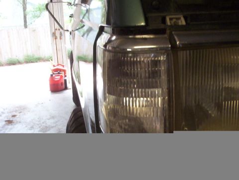 1989 Ford Bronco - Close-up of the front corner of a 1989 Ford Bronco, showing the headlight and clear turn signal assembly.