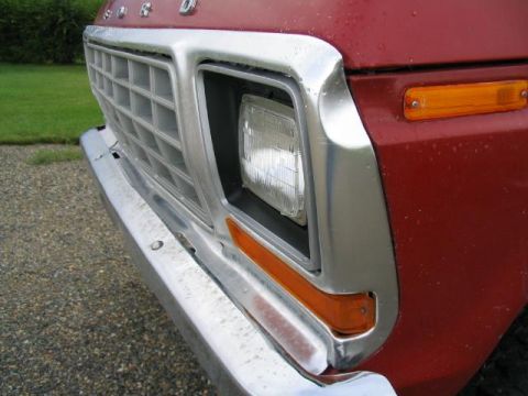 1979 Ford F-150 - Close-up of the front grille and headlight assembly on a red 1979 Ford F-150 truck.