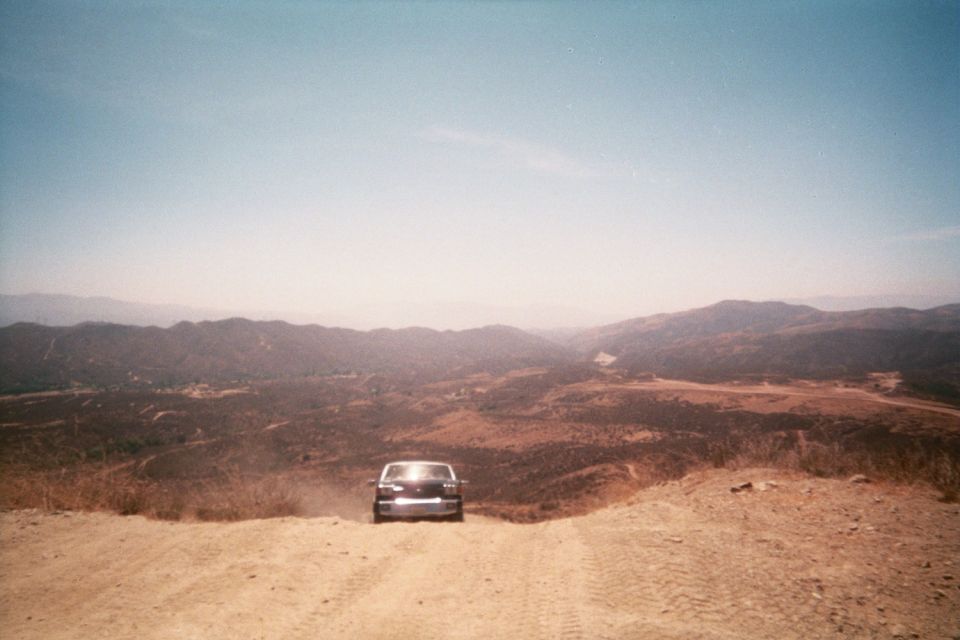 vehicle on a dirt road atop a ridge overlooking dry mountain valleys