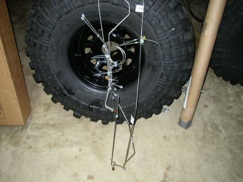 1995 Ford Bronco - Metal brake lines are displayed in front of a large off-road tire, suggesting automotive parts.