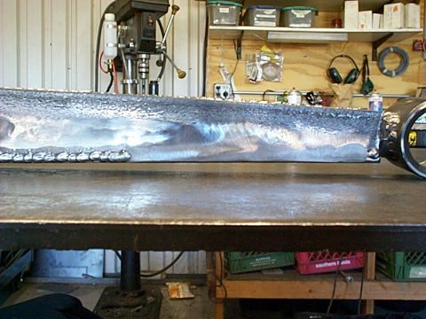 1994 Ford Bronco - A close-up view of a metal pipe section with visible welds, resting on a workbench.