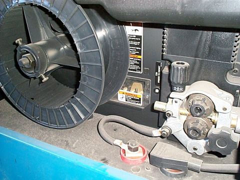 1994 Ford Bronco - Close-up of a wire feeder mechanism, showing the spool of welding wire and the drive rollers.