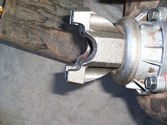 Driveshaft yoke connected to a differential housing, resting on a wooden surface