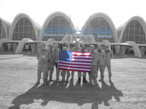 1988 Ford Bronco - Group of soldiers holding the American flag in front of the distinctive architecture of Kandahar International Airport.