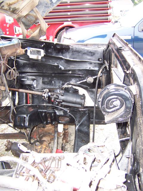 1979 Ford F-150 - Close-up of the engine bay, focusing on steering components and a horn, with other vehicles in the background.