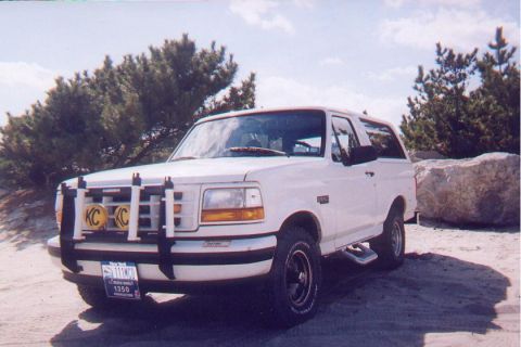 1996 Ford Bronco - This 1996 Ford Bronco is parked on a sandy terrain with sparse vegetation and large rocks.