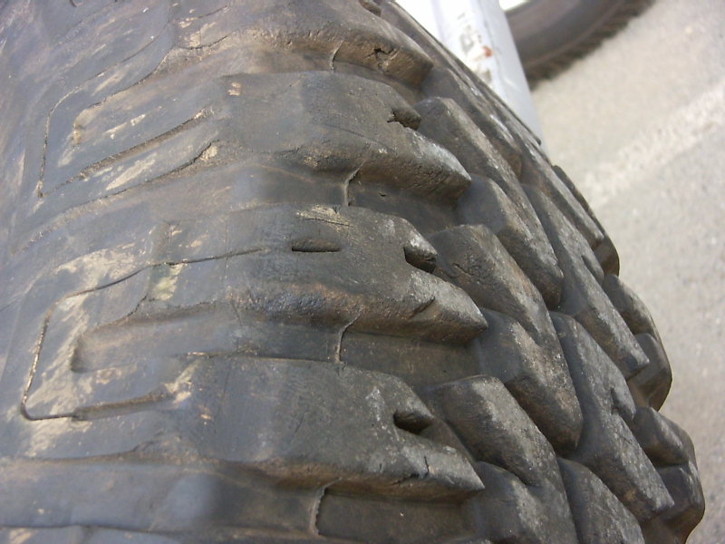 Close-up of a worn, aggressive tire tread with large blocks and deep grooves