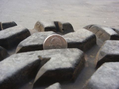 1990 Ford Bronco - Tire tread detail with a quarter coin for size comparison.